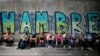 Manifestantes antigubernamentales descansan bajo un puente y un letrero que denuncia el hambre en Venezuela, en julio de 2017.