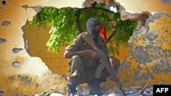 FILE - A Somali soldier stands guard next to the site where al-Shabab militants carried out a suicide attack against a military intelligence base in Mogadishu, June 21, 2015.