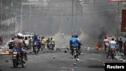Warga Haiti melewati barikade di sebuah jalan di Port-au-Prince, Haiti, 8 Juli 2018.
