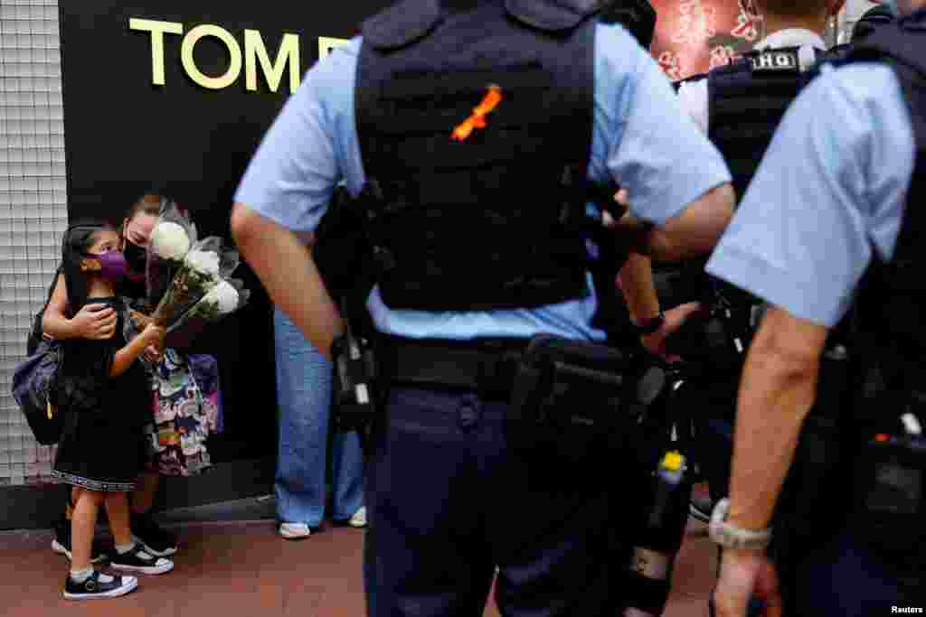 A mother and child holding flowers are stopped by police as they try to pay tribute to a man, who stabbed a policeman then stabbed himself and died on the anniversary of the city's return to Chinese rule, at Causeway Bay in Hong Kong, China.