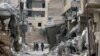 FILE - Fighters from Syrian Democratic Forces walk together along a damaged street in Raqqa, Syria, Sept. 16, 2017. The unidentified American being held in Iraq as an enemy combatant was captured in Syria in September by the SDF.