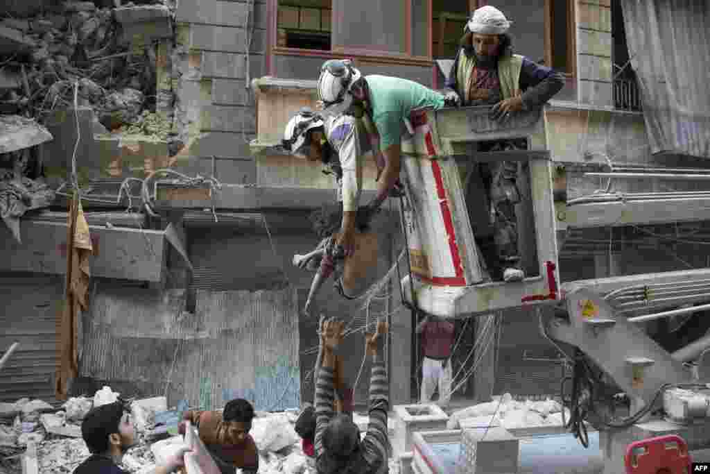 Petugas penyelamat Suriah menyerahkan jenazah seorang anak perempuan kepada warga sipil di bawah puing-puing gedung yang hancur karena serangan udara i Al-Shaar di Aleppo. (AFP/Karam al-Masri)