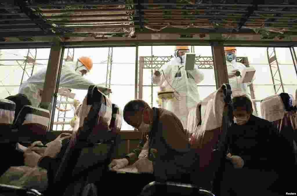 Para pekerja melaksanakan screening radiasi terhadap bus yang dipakai oleh pekerja media untuk tur di PLTN Fukushima Daiichi di Fukushima, Jepang, menjelang ulang tahun kedua bencana tsunami dan gempa yang terjadi 11 Maret 2011.