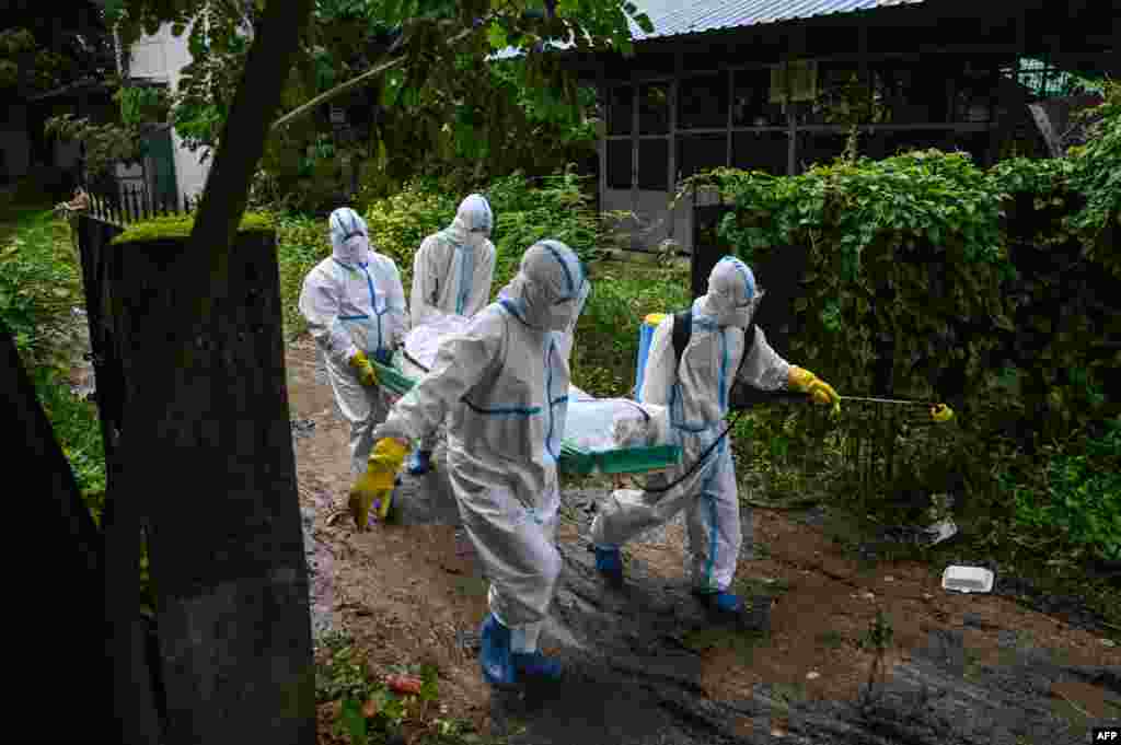 Volunteers wearing personal protective equipment carry the body of a victim of the Covid-19 to a cemetery in Hlegu Township in Yangon, Myanmar, July 10, 2021.