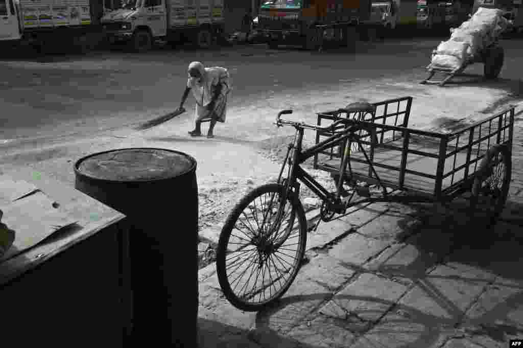 A woman collects slaked lime from the ground at a wholesale market during a 15-day lockdown announced by West Bengal's government to curb the spread of the COVID-19 disease, in Kolkata, India.
