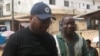 FrontPage Africa editor Rodney Sieh (left) escorted by a marshal (right)