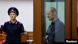 El reportero del Wall Street Journal, Evan Gershkovich, que está siendo juzgado por cargos de espionaje, reacciona dentro de un recinto para los acusados ​​antes de una audiencia judicial en Ekaterimburgo, Rusia, el 26 de junio de 2024.