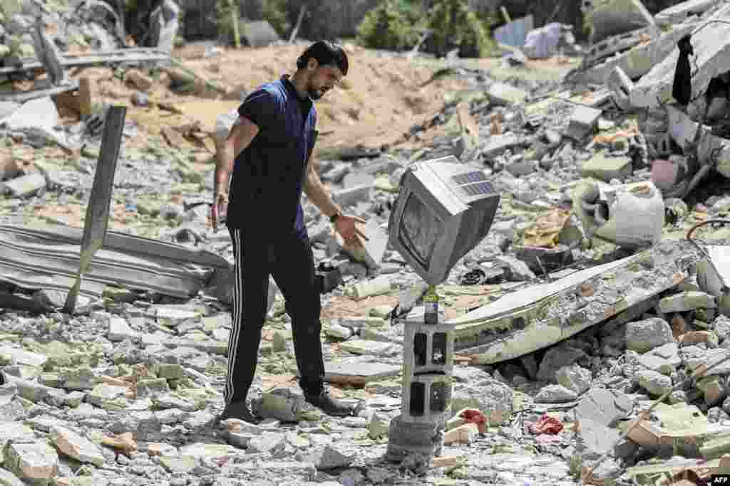 Palestinian performance artist Mohammed al-Shenbari stacks up a television atop a bottle as he demonstrates his skills in balancing objects, in the ruins of houses destroyed by Israeli air strikes the May 2021 conflict between Israel and Hamas, in Beit Lahia in the northern Gaza Strip, July 6, 2021. 