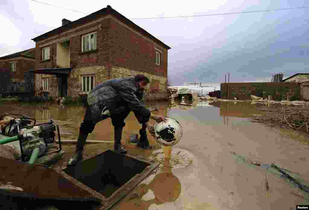 Seorang pria menguras air keluar dari rumahnya yang kebanjiran di Murtino, 180 kilometer timur ibukota Skopje, Macedonia.