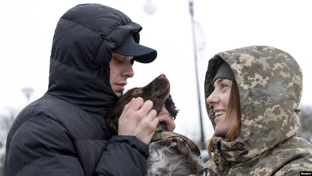 Illija Muzika (29) i Alina Panina (27), ukrajinski graničari i bivši ratni zarobljenici igraju se sa njenim psom Roksi, nakon što su oboje pušteni iz zatočeništva, 23. januara 2024. (Foto: Rojters/Valentyn Ogirenko)