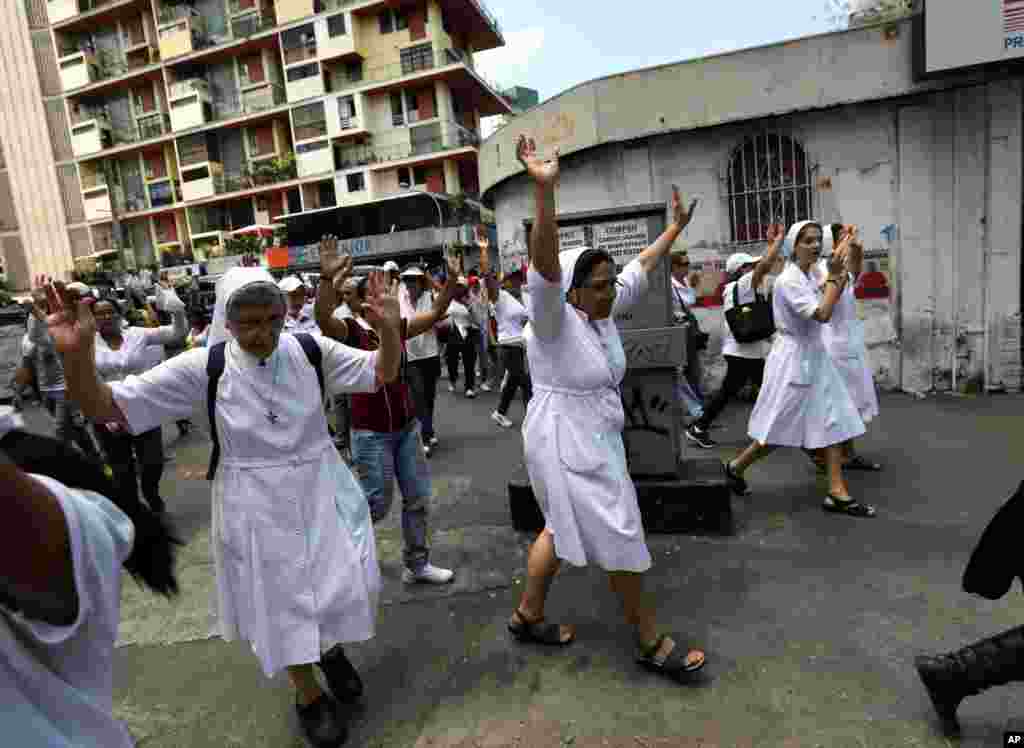 Freiras levantam os seus braços durante uma marcha em protesto à repressão do Governo sobre as manifestações do povo em Caracas, Fev. 26, 2014.