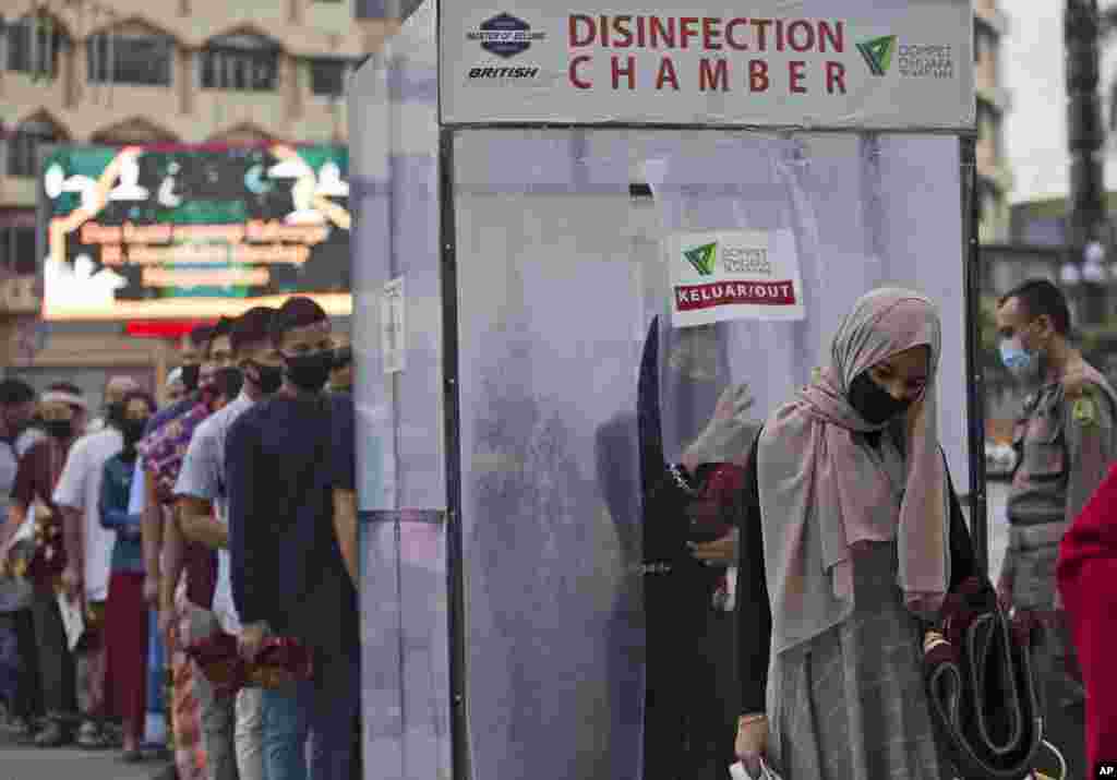 Muslims queue up to enter a disinfection chamber set up as a precaution against the new coronavirus outbreak, prior to entering Al Mashun Grand Mosque's compound to attend an Eid al-Adha prayer in Medan, North Sumatra, Indonesia.