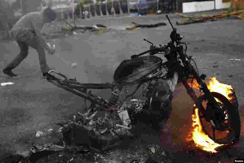 Um manifestante corre por trás de uma motorizada que arde durante um protesto em San Cristobal, Venezuela, Fev. 27, 2014.