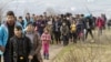FILE - Refugees and migrants, mostly from Afghanistan, walk toward the transit center for refugees near the northern Macedonian village of Tabanovce, after being returned from Serbia, Feb. 22, 2016.