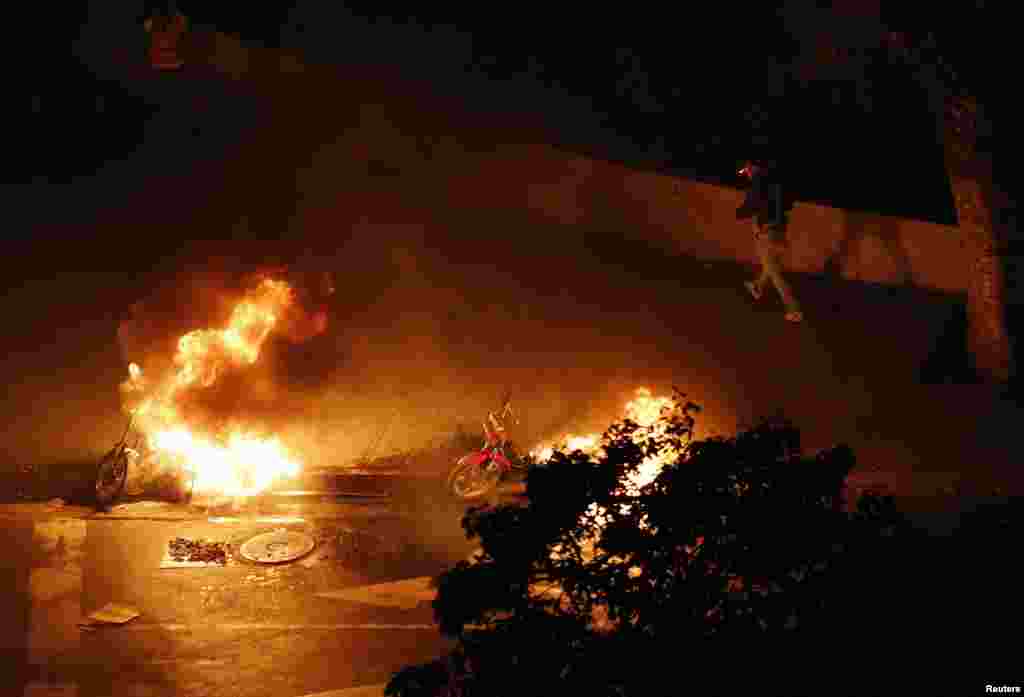 Um motociclista passa por motorizadas incendiadas por manifestantes anti-governo na Praça de Altamira em Caracas, Fev. 26, 2014. 