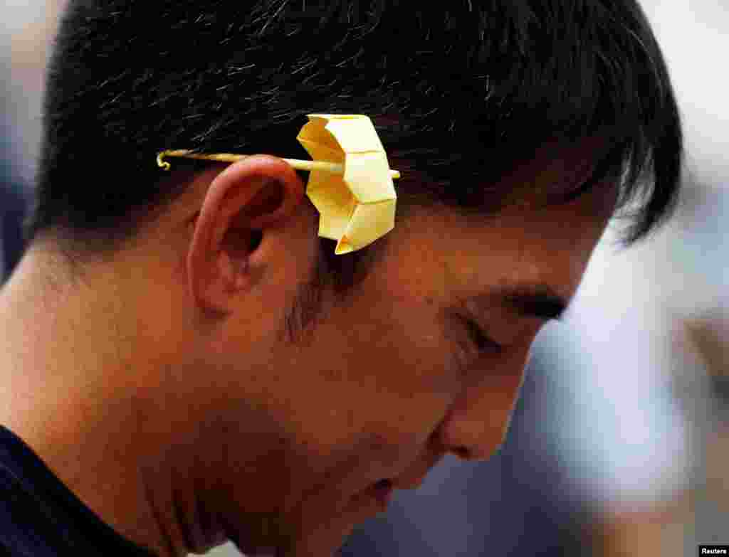 Seorang pria dengan payung origami berwarna kuning, simbol dari gerakan penentangan rakyat, yang dikenal dengan Occupy Central, mengambil bagian dalam peringatan tahun kedua gerakan tersebut di luar kantor pusat pemerintah di Hong Kong.