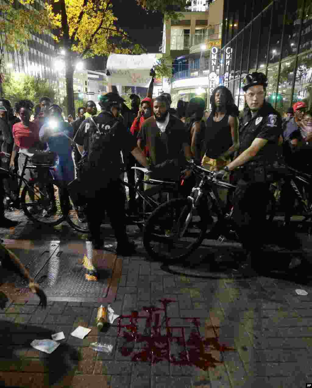 Polisi mengelilingi tempat genangan darah setelah seorang pria terluka dalam demonstrasi menentang penembakan fatal oleh polisi di Charlotte, North Carolina (21/9). (AP/Chuck Burton)