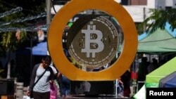 ARCHIVO - Una mujer pasa por el Monumento a Bitcoin después de que la moneda virtual se disparara por encima de los 100.000 dólares. En Ilopango, El Salvador, el 5 de diciembre de 2024. 