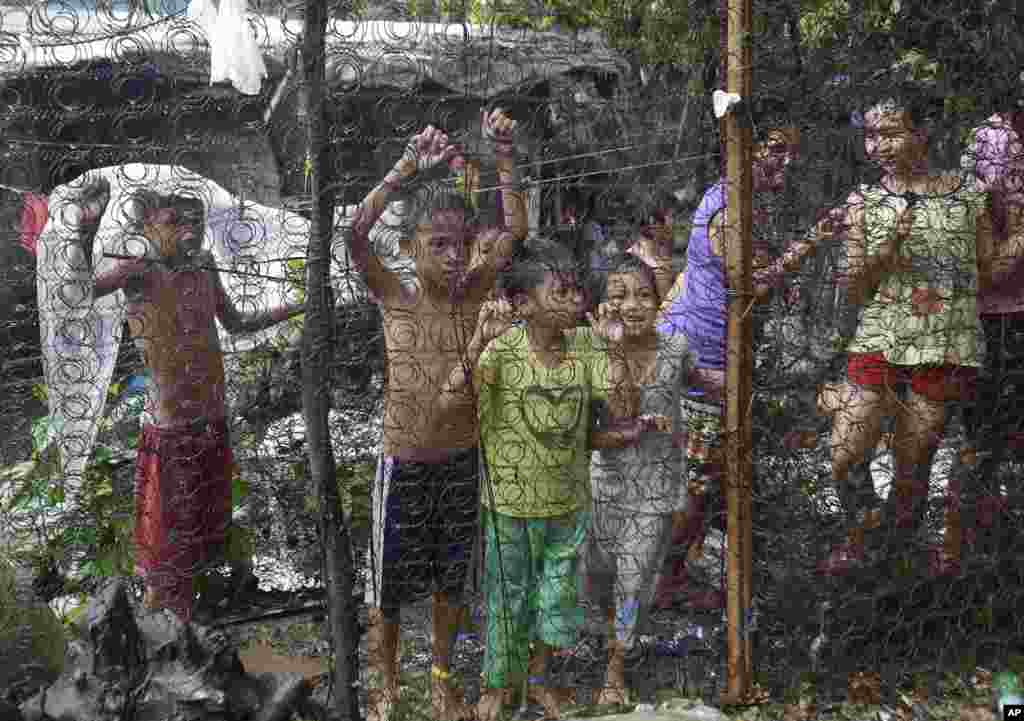 Children watch as arrested drug suspects, not shown, wait outside an alleged drug den following a raid near the Payatas dumpsite in suburban Quezon city, north of Manila. Two suspects were killed and about 90 people arrested during "War on Drugs" campaign of Philippine President Rodrigo Duterte.