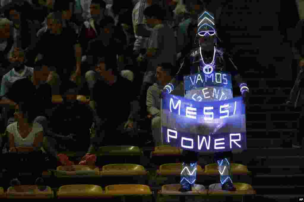 An Argentina fan holds a national flag with a lighted sign in support of star player Lionel Messi, prior to a 2018 World Cup qualifying soccer match against Paraguay, in Cordoba, Argentina, Oct. 11, 2016.