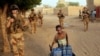 French soldiers patrolling the streets of Gao, Mali, walk past a boy carrying canisters on Dec. 4, 2021.