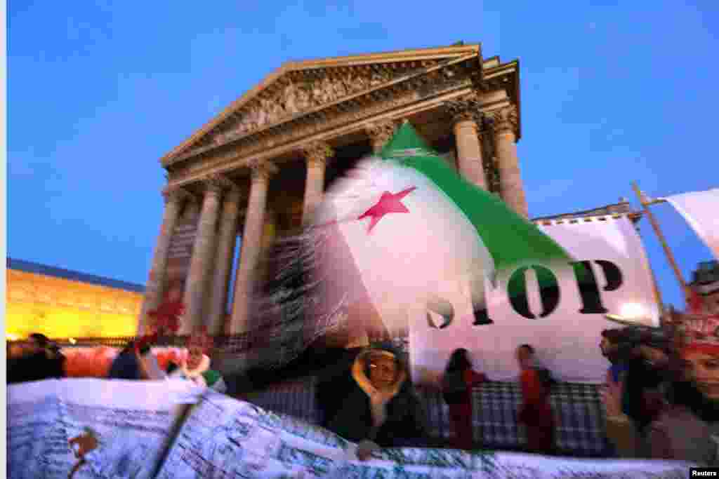 Seorang demonstran melambai-lambaikan bendera Suriah selama protes melawan kekerasan di Suriah di depan Pantheon di Paris (15/3). (Reuters/Philippe Wojazer)