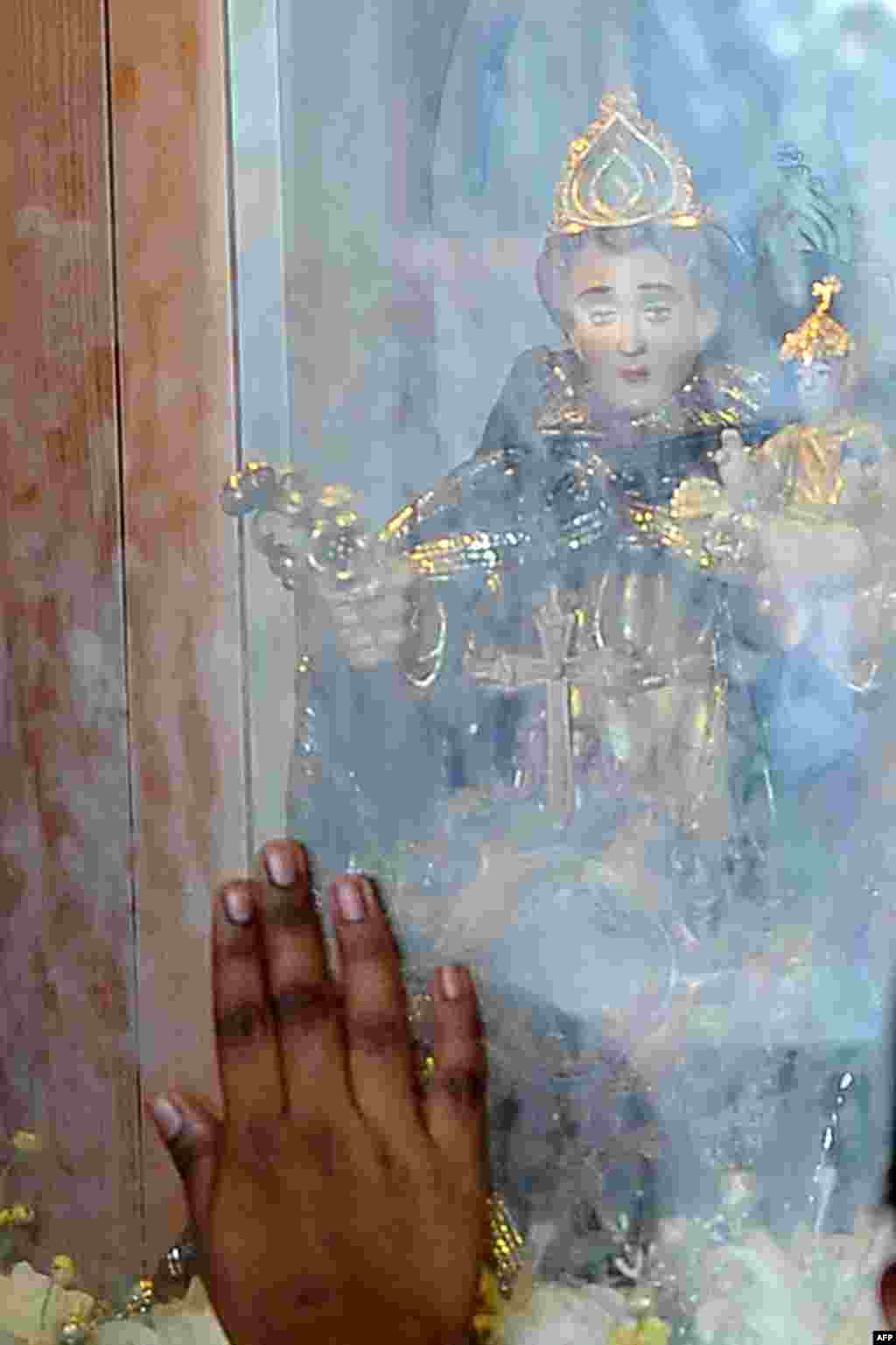 Seorang Katolik Sri Lanka menyentuh kaca dekat patung selama misa di sebuah gereja di Kolombo.