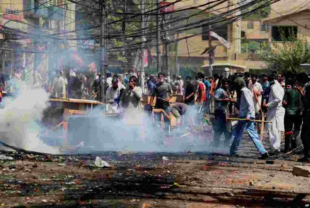 Supporters of an anti-Taliban cleric hurl stones toward police during clashes in Lahore, Pakistan, June 17, 2014.