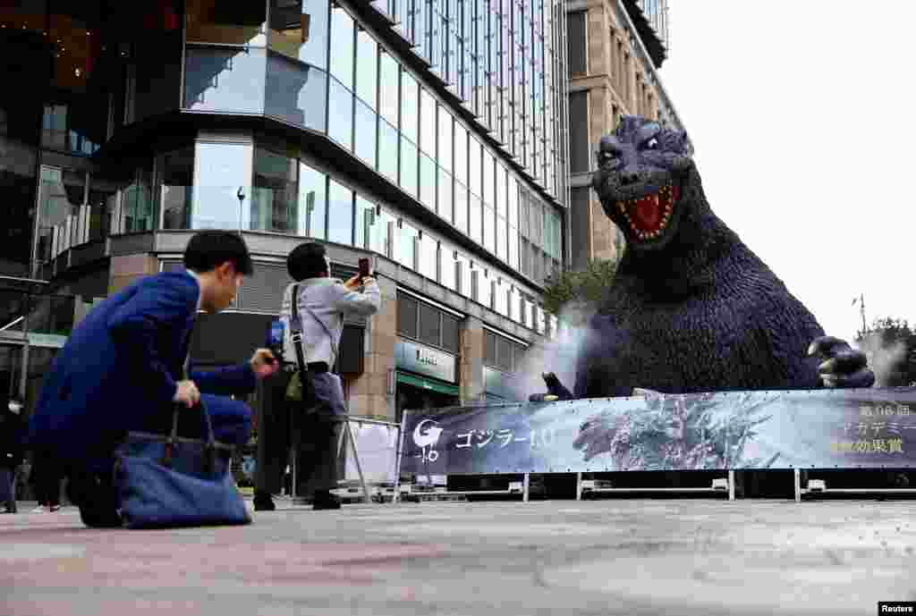 People take photos of a Godzilla statue which is installed to promote the film 'Godzilla Minus One' in Tokyo, after the movie won the Oscar for Best Visual Effects at the 96th Academy Awards in Hollywood.