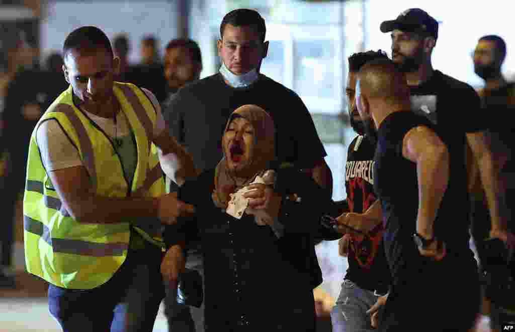 Palestinians assist a wounded woman amid clashes with Israeli security forces in Jerusalem's Old City, May 8, 2021.