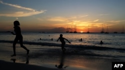 ARCHIVO - Turistas en una playa de Bridgetown, Barbados, en el atardecer del 24 de marzo de 2017. Barbados ha anunciado su intención de convertirse en república en noviembre de 2021.