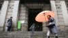 日本中央银行出人意料地决定将利率降至-0.1%。图片显示２０１６年１月２９日一名打伞妇女经过日本央行门前。