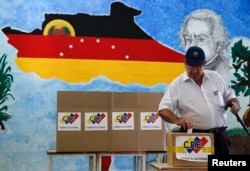A man casts his ballot in a box during a municipal elections in Caracas, Venezuela, Dec. 8, 2013.