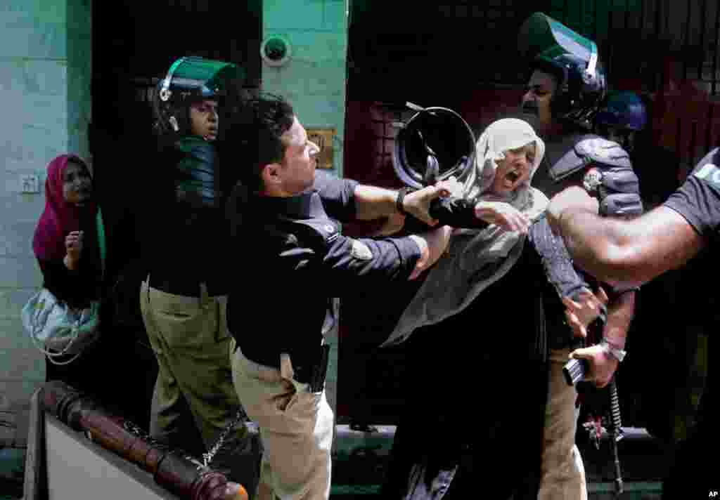 A police officer scuffles with a protester during clashes in Lahore, Pakistan, June 17, 2014.