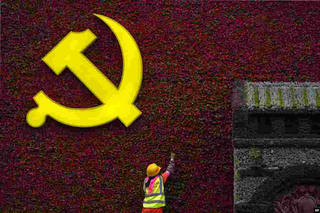 A worker installs a flag-shaped flowers decoration with a Communist Party's logo in Beijing, China.
