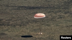 La cápsula Soyuz con tres astronautas a bordo desciende con ayuda de un paracaídas en las estepas de Kazijistán el 17 de abril de 2020.