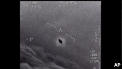 FILE - Image from video provided by the Department of Defense labelled Gimbal, from 2015, an unexplained object is seen at center as it is tracked as it soars high along the clouds, traveling against the wind.