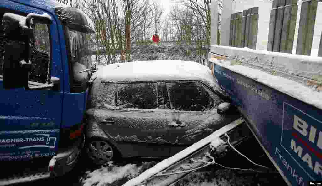 Seorang petugas penyelamat berdiri di samping puing-puing mobil menyusul kecelakaan di jalan raya antara Giessen dan Hanau, dekat kota Woelfersheim, Jerman. Lebih dari 100 mobil terlibat dalam tabrakan beruntun akibat kondisi jalan raya bersalju.
