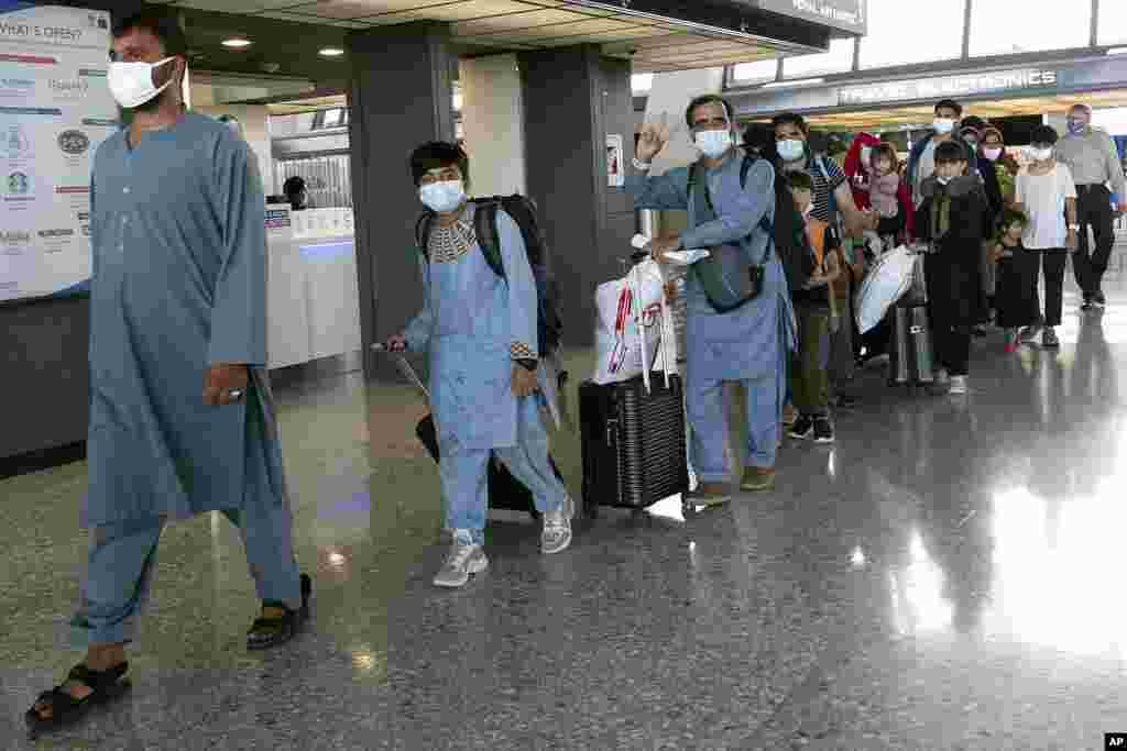 Families evacuated from Kabul, Afghanistan, walk through the terminal before boarding a bus after they arrived at Washington Dulles International Airport, in Chantilly, Virginia.