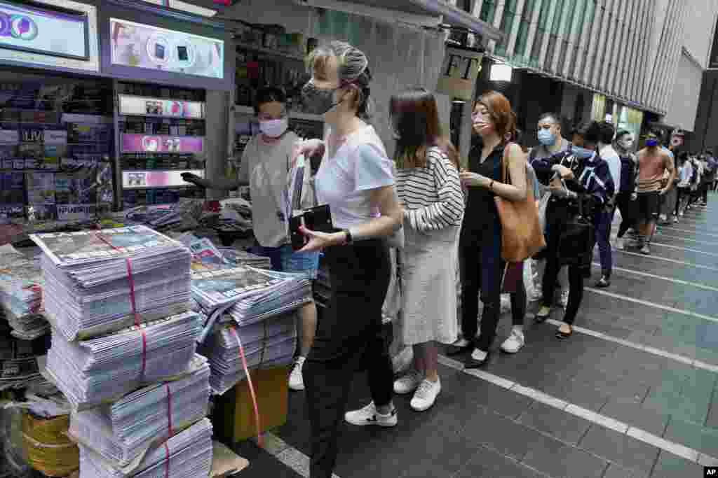 People queue up for last issue of Apple Daily at a newspaper booth at a downtown street in Hong Kong. The last remaining pro-democracy newspaper will stop publishing, following last week's arrest of five editors and executives and the freezing of $2.3 million in assets under the city's one-year-old national security law.