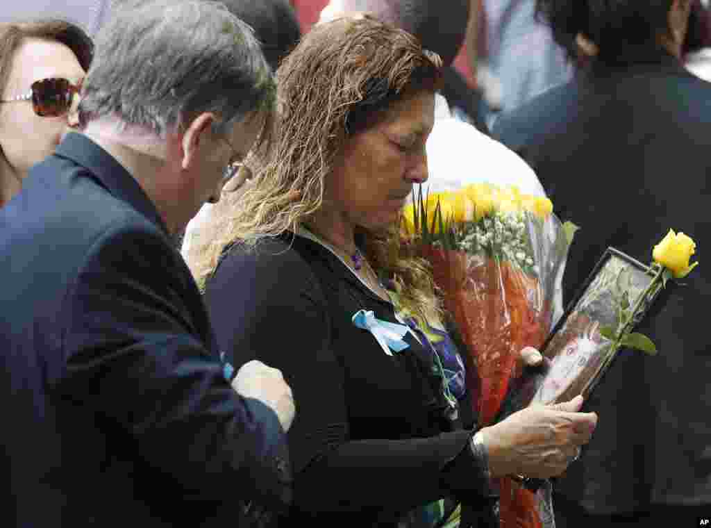 Seorang warga memegang foto orang yang dikasihi dalam acara peringatan serangan 11 September di World Trade Center di Memorial Nasional 11 September di New York (11/9). (AP/Mary Altaffer)