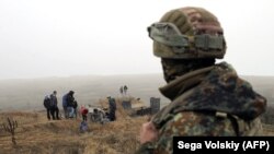 UKRAINE -- A Ukrainian serviceman looks at activists digging trenches on the coast of the Sea of Azov near the Ukrainian city of Mariupol, November 26, 2018.