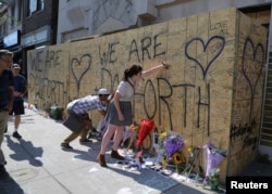 People write messages on construction boarding after a mass shooting on Danforth Avenue in Toronto, Canada, July 24, 2018.