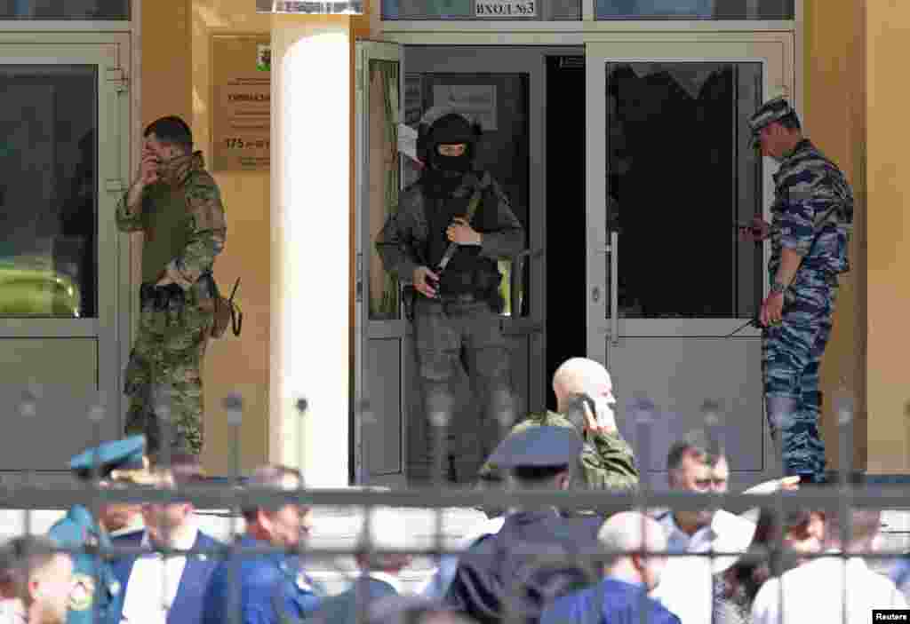 Law enforcement officers stand next to the entrance of School Number 175 after a deadly shooting in Kazan, Russia. At least seven students, one teacher and another worker were fatally shot when a gunman opened fire at an elementary school.