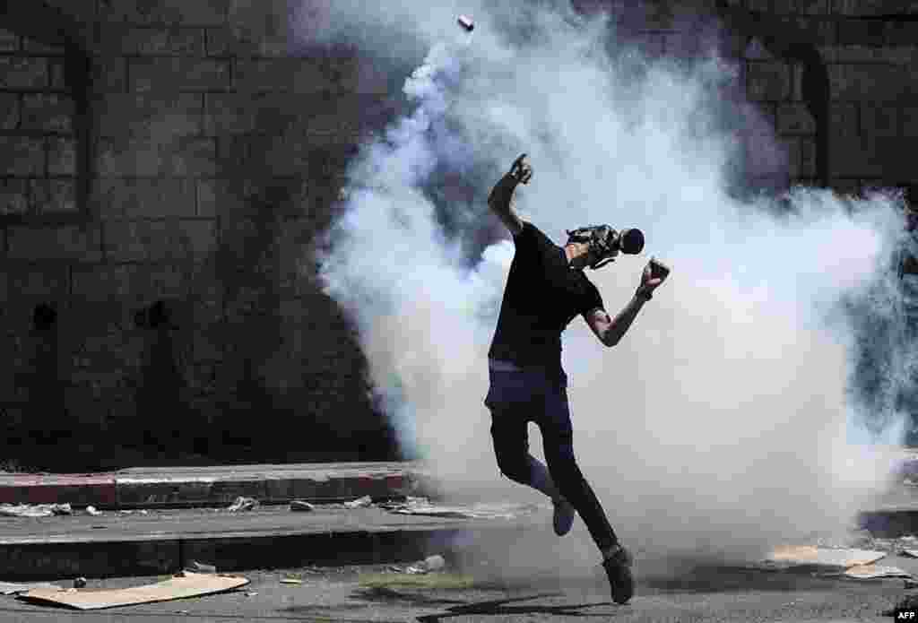 A Palestinian demonstrator returns a tear gas canister fired by Israeli security forces during clashes following a protest against Israeli settlements in the village of Beita near the occupied West Bank city of Nablus.