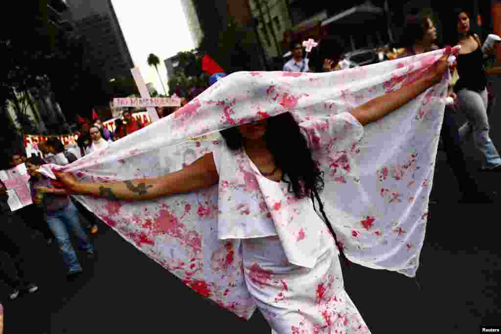 Seorang perempuan memegang sehelai kain yang penuh noda seperti darah dalam demonstrasi menuntut keadilan bagi perempuan korban kekerasan di Mexico City, Meksiko (8 Maret 2013).