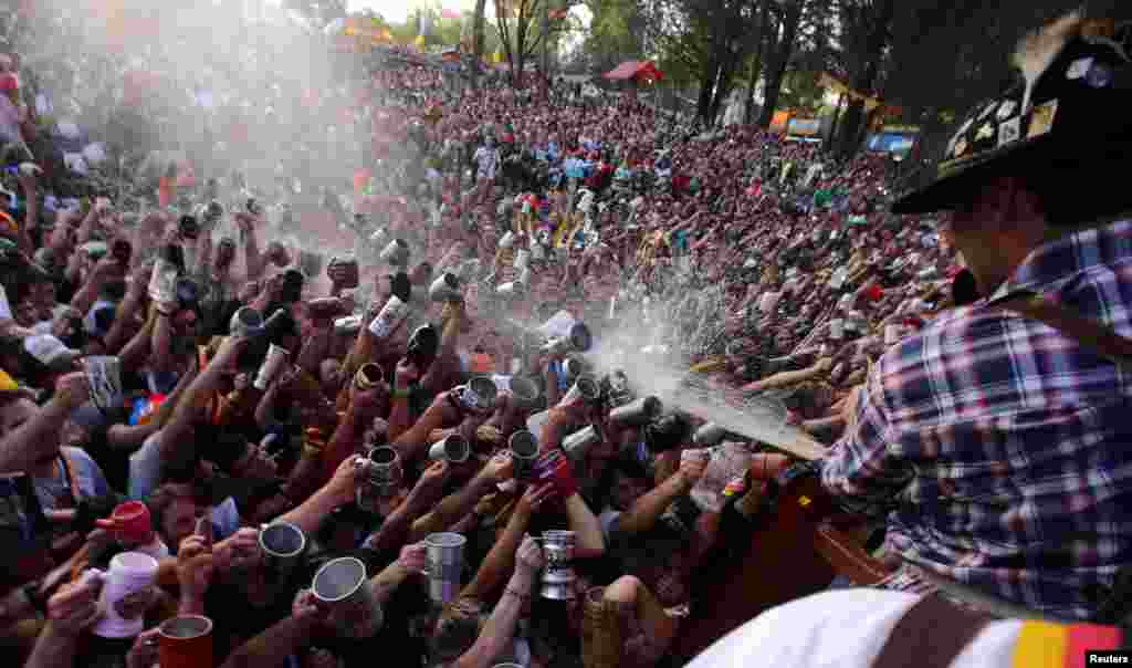 Visitors try to fill their mugs as beer is sprayed on them from a barrel at Argentina's Oktoberfest, the national beer festival, in Villa General Belgrano, Argentina, Oct. 9, 2016.