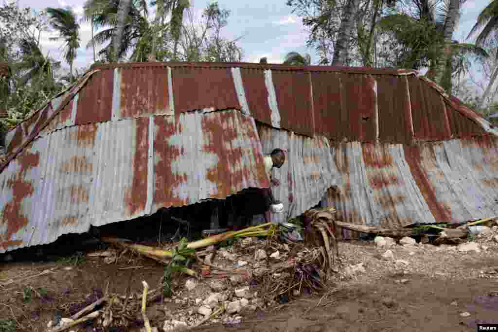 Seorang perempuan keluar dari rumahnya yang hancur oleh Badai Matthew di Cavaillon, Haiti (6/10). (Reuters/Andres Martinez Casares)