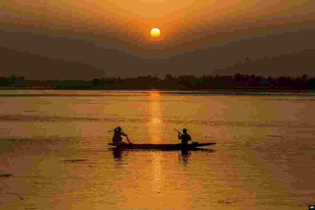 Seorang nelayan menarik jala dari atas perahunya saat matahari terbenam di Danau Dal, Srinagar, Kashmir-India.