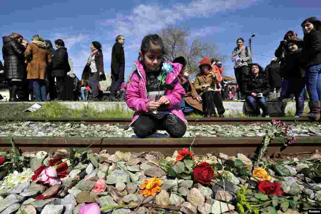 Seorang gadis cilik meletakkan setangkai bunga di jalur kereta api di stasiun kereta api tua di Thessaloniki, Yunani, dalam peringatan ulang tahun ke-70 deportasi pertama warga Yahudi dari Thessaloniki ke Auschwitz.